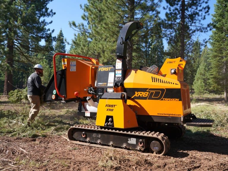 Operator feeding brush into a Först tracked wood chipper on a forestry job